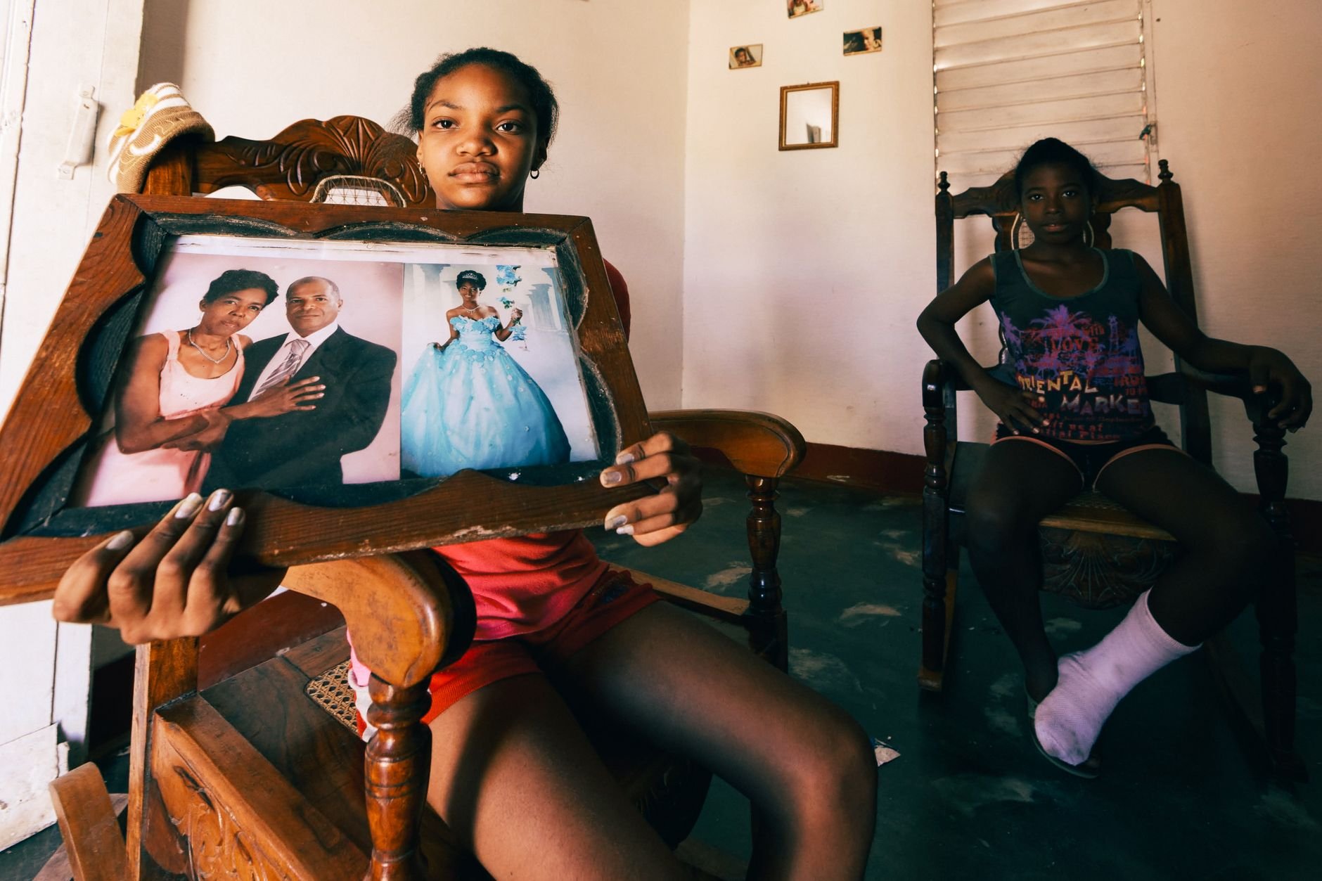 Two girls holding a framed family portrait, showcasing a cherished memory.