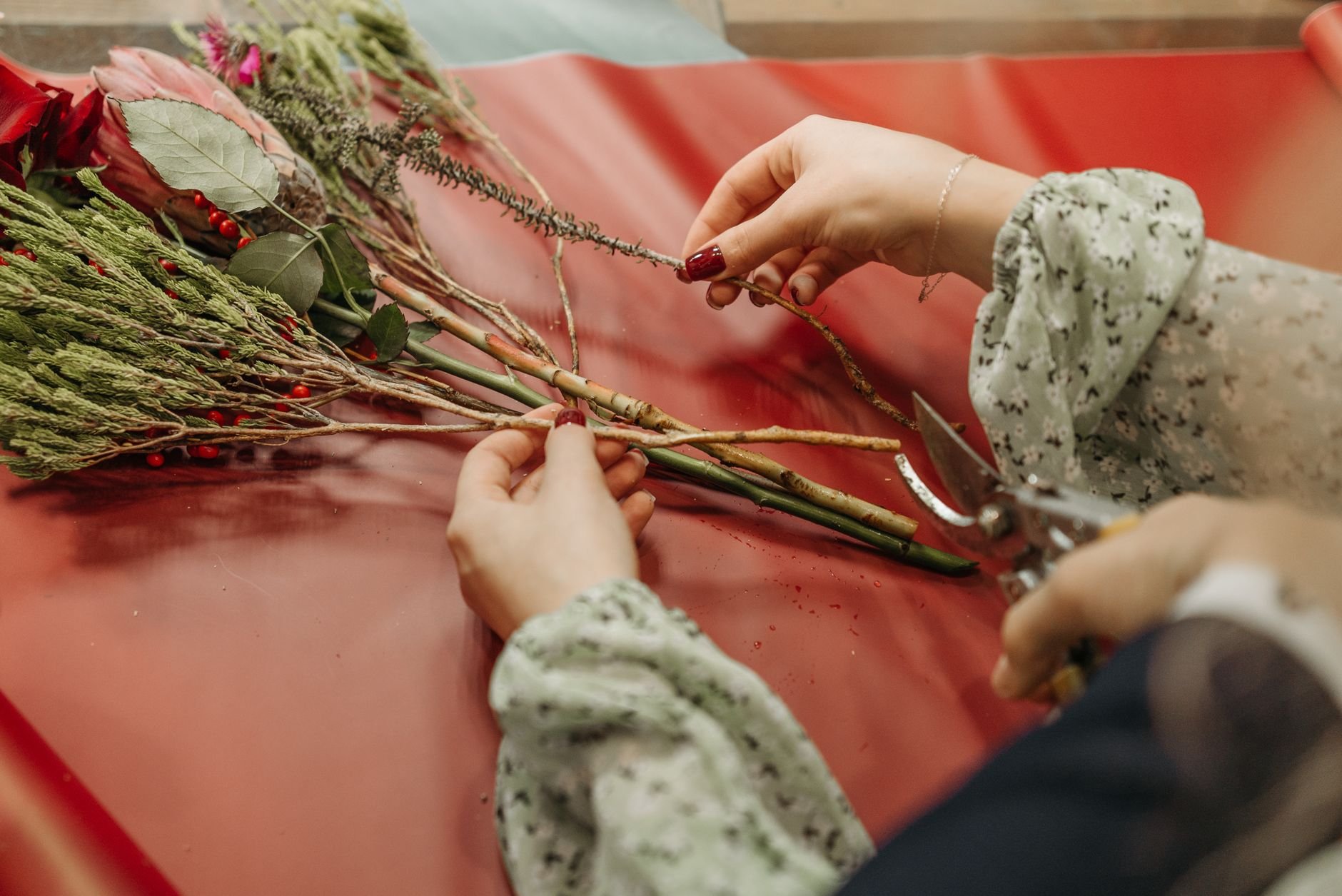 Close-up of hands arranging flowers, emphasizing creativity and craft.